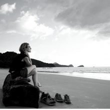 Frau sitzt einsam am Strand